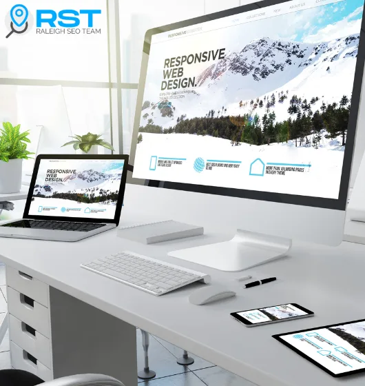 Desktop and laptop displaying "Responsive Web Design" on screens, with mobile devices nearby, in a modern office setting, emphasizing Raleigh SEO Team's focus on mobile-first web design and user experience.