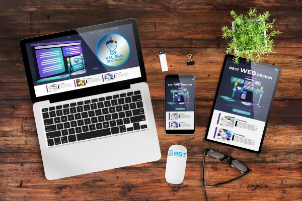 Laptop and smartphone displaying Raleigh SEO Team branding and web design concepts, surrounded by office supplies and a plant, illustrating smart site development and digital marketing solutions.