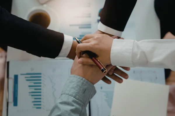 Hands joining together over a table with charts and graphs, symbolizing collaboration and partnership in business growth strategies.