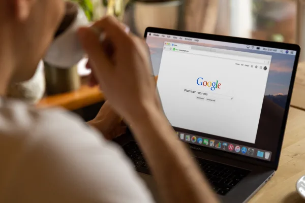 Person using a laptop to search on Google, illustrating the importance of SEO for online visibility and customer engagement for small businesses.